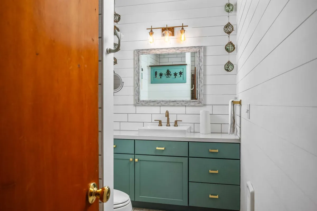 A bright, modern bathroom with a vanity, sink, mirror, and elegant light fixtures. The clean design and calming ambiance suggest spa-like relaxation and convenience for guests.